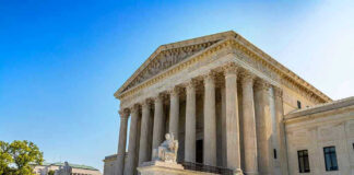 Stone building with columns and statues, clear blue sky.