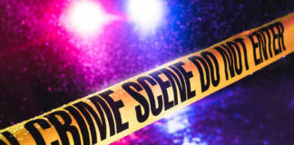 Crime scene tape with flashing lights in background