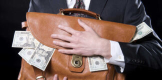Person clutching leather bag with money sticking out.