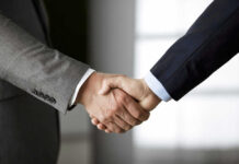 Two people in business suits shaking hands.