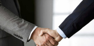 Two people in business suits shaking hands.