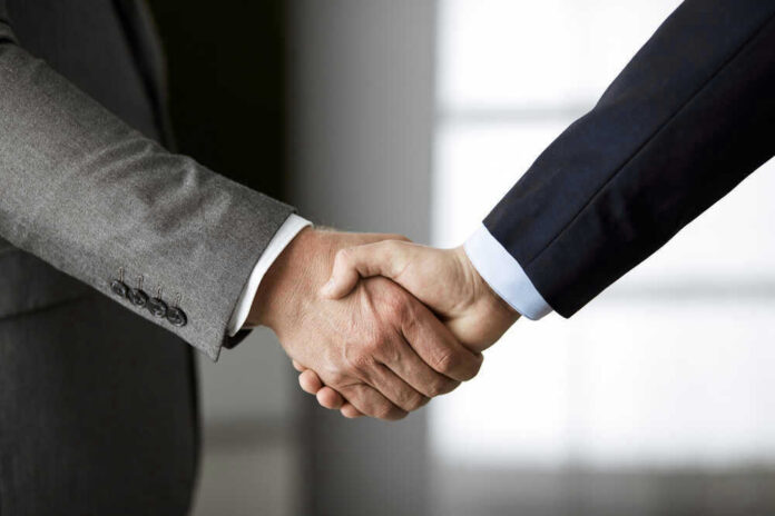 shutterstock_1726494064.jpg Two people in business suits shaking hands.