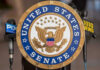 United States Senate seal with microphones in front.