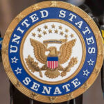 Shockwaves: Senate Run To Remove Old-Timer United States Senate seal with microphones in front.