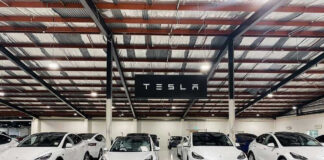 White Tesla cars displayed in showroom with Tesla sign