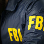 Homecoming Horror — 5 Nabbed by FBI FBI agent in navy blue jacket