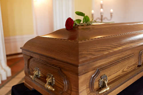 shutterstock_741689236.jpg A wooden casket with a red rose placed on top