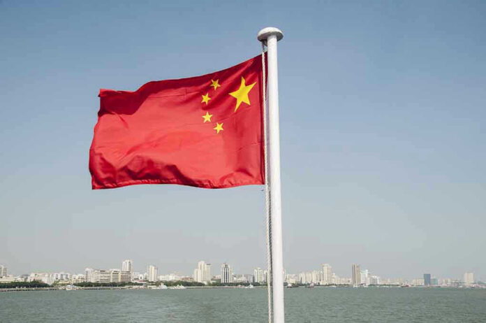 Chinese flag waving over cityscape and water.