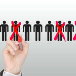 Hand crossing out stick figures with a red marker.