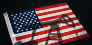 American flag with oil pump shadow overlay.