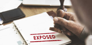 A hand stamping the word 'EXPOSED' on a document