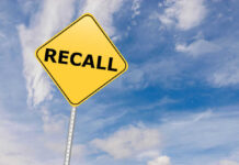 Massive Recall: Bacteria ALERT! Yellow sign with RECALL text against blue sky.
