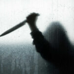Backlit silhouette holding a knife through frosted glass.