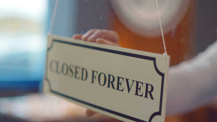 shutterstock_1836658408.jpg Closed forever sign being placed on window.