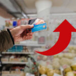 Hand holding credit cards with red upward arrow