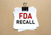 FDA’s URGENT Alert: Cheese Danger A notice labeled 'FDA RECALL' clipped to white papers on a brown background