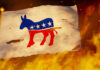 Probe Backfires On Democrats Torn Democratic flag burning amid flames and embers.