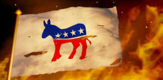 Torn Democratic flag burning amid flames and embers.