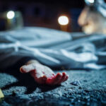 Crime scene with covered body and hand exposed.