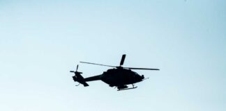 Silhouette of a helicopter flying against a light sky