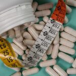 New Obesity Pill Stuns Industry White capsules scattered around a measuring tape and a bottle