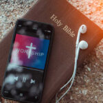 Christian Music EXPLODES — Pop Dominance CRUMBLES Smartphone displaying worship music on top of a Holy Bible