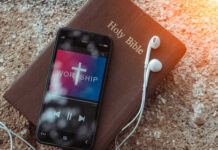 Smartphone displaying worship music on top of a Holy Bible