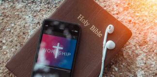 Smartphone displaying worship music on top of a Holy Bible