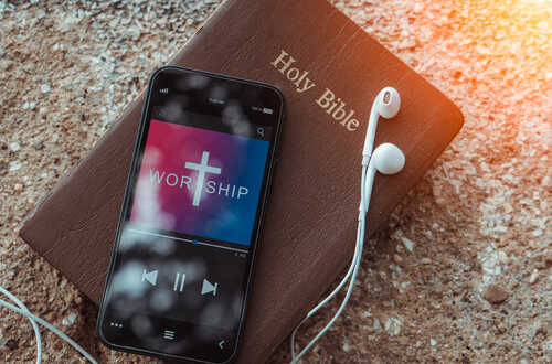 shutterstock_1990473506 (1).jpg Smartphone displaying worship music on top of a Holy Bible