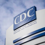 CDC Alert: 30 States in Crisis Mode! CDC building sign against a cloudy sky.