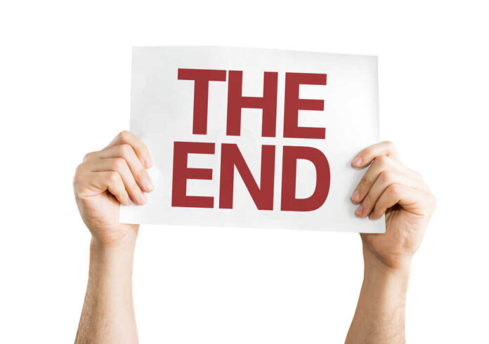 shutterstock_252362974.jpg Hands holding a sign that reads 'THE END'