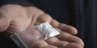 Hand holding small bag of white powder.