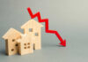 Wooden model houses with a red downward trend arrow