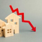 ALARMING Housing Collapse Despite Lowest Rates Since 2022 Wooden model houses with a red downward trend arrow