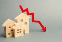 Wooden model houses with a red downward trend arrow