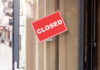 A red 'CLOSED' sign hanging on a storefront door