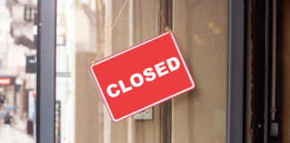 A red 'CLOSED' sign hanging on a storefront door