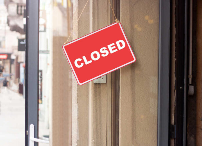 shutterstock_1684013713.jpg A red 'CLOSED' sign hanging on a storefront door
