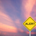 Crime Shocker: Savannah Guthrie’s Mom Missing Yellow alert sign against a colorful sunset sky