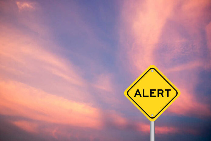 shutterstock_1814257538.jpg Yellow alert sign against a colorful sunset sky