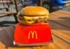 A cheeseburger from McDonald's placed on a red box on a wooden table