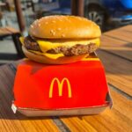 A cheeseburger from McDonald's placed on a red box on a wooden table
