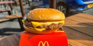 A cheeseburger from McDonald's placed on a red box on a wooden table