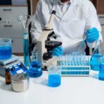 Scientist in a lab working with blue liquids and a microscope