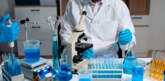 Scientist in a lab working with blue liquids and a microscope