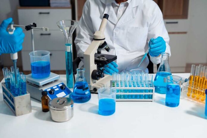 Scientist in a lab working with blue liquids and a microscope