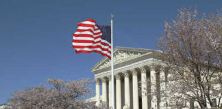 U.S. Supreme Court building with an American flag and cherry blossom trees