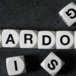 White letter blocks spelling 'PARDON' on a black surface