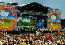 A large crowd at an outdoor music festival with a vibrant stage