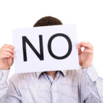 Iran’s “NO” Torpedoes White House Plan? Person holding a sign that says 'NO' in large letters